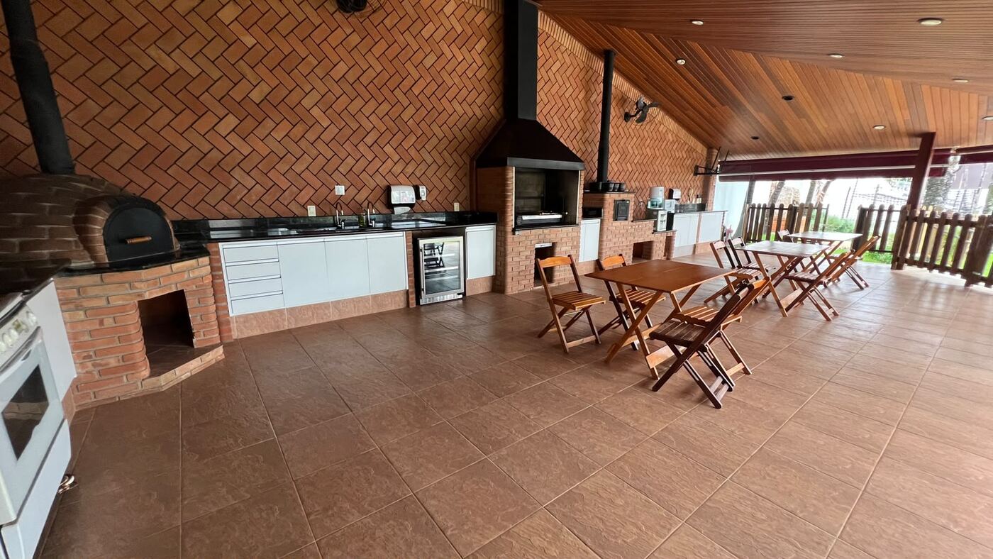 Área gourmet com churrasqueira, forno e mesas