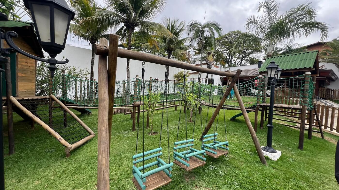 Playground de madeira com balanços e casinha